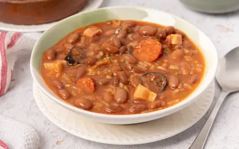 Un tazón de judías pintas con chorizo, patatas y arroz en un guiso meloso.