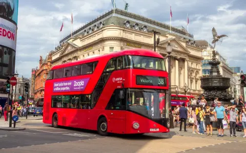 Czerwony piętrowy autobus w Londynie na tle Piccadilly Circus.