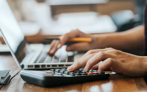 Hände bedienen Laptop und Taschenrechner. So lässt sich die Kaution in Raten zahlen und die Finanzen im Blick behalten.