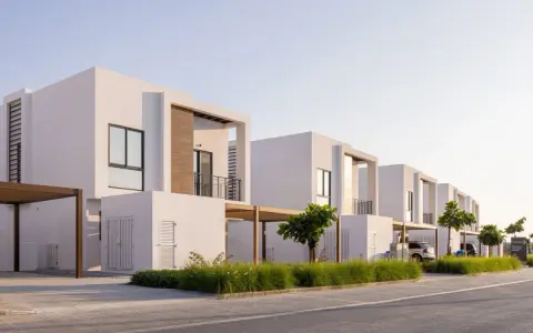 Frente fachadas de casas modernas con líneas limpias y detalles en madera. Un camino de adoquines y césped verde adornan el exterior.