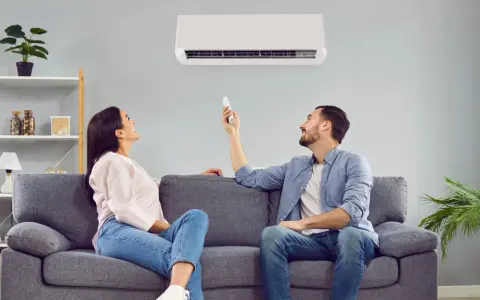 Pareja ajustando el aire acondicionado para encontrar la temperatura ideal y ahorrar energía.