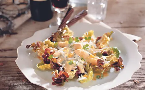 Omas Spargelsalat mit cremigem Dressing, Eiern und Kräutern, serviert auf einem weißen Teller mit Salatblättern.
