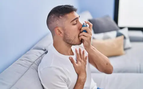 Mężczyzna używa inhalatora, szukając ulgi w objawach astmy. Leki na astmę bez recepty mogą pomóc w łagodzeniu napadów.