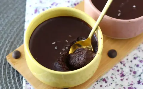 Delicioso mousse de chocolate en un cuenco amarillo, con una cuchara dorada lista para probarlo. ¡Un placer para los sentidos!