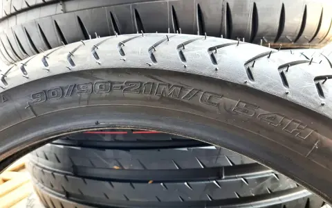Profil opony 90/90-21M/C 54H. Widok z bliska na bieżnik i oznaczenia rozmiaru opony motocyklowej.