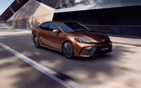 Brązowa Toyota Camry Hybrid w ruchu. Sprawdź aktualną toyota camry cena i wybierz swój wymarzony model.
