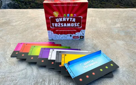 Gra "Ukryta tożsamość" w pudełku i kolorowe karty do gry.