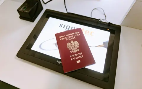 Polski paszport na ekranie tabletu w biurze paszportowym w Poznaniu. Obok skaner linii papilarnych.