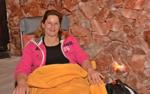 Entspannte Frau in der Bad Salzuflen Salzgrotte, umgeben von rosa Salzsteinen.