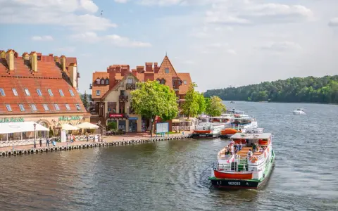 Port w Giżycku, gdzie cumują statki wycieczkowe, to jedna z głównych atrakcji miasta. W tle malownicze kamieniczki i zielone lasy.
