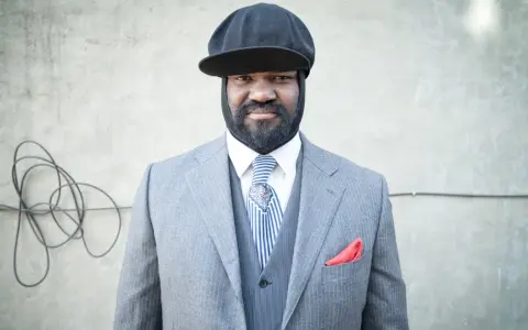 Gregory Porter w eleganckim garniturze i czapce, gotowy na koncert.