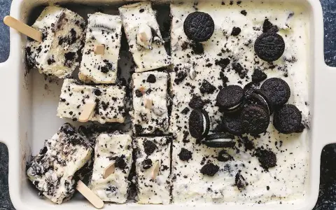 Oreo glass recept: krämig glass med krossade Oreos och hela kakor, skuren i bitar med träpinnar. Perfekt sommardessert!