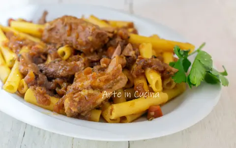 Piatto di ziti alla genovese con ragù di carne e cipolle caramellate, guarnito con prezzemolo fresco.