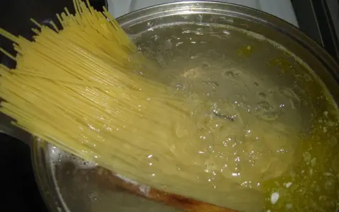 Długi makaron spaghetti gotuje się w bulgoczącej wodzie. Czas, **ile gotować makaron**, zależy od jego grubości.