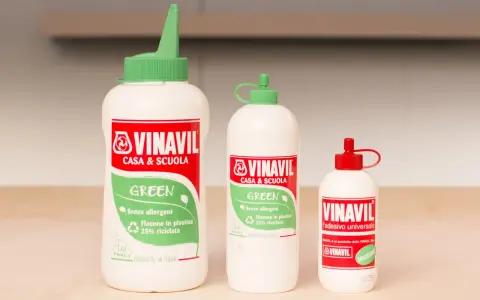 Tre flaconi di colla Vinavil, un adesivo universale pva glue cos'è, in diverse misure, con tappi verdi e rossi.