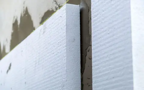 Aislamiento de poliestireno expandido en una pared, paso clave para **edificios eficientes** y confortables.