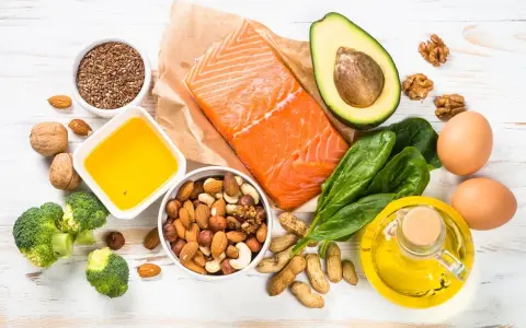 Assortiment d'aliments riches en oméga 9 : saumon, avocat, noix, amandes, graines de lin, brocolis, œufs, huile d'olive.
