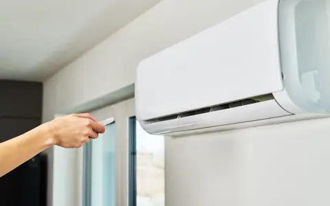 Main tenant utilise la télécommande pour régler le voyant clim.
