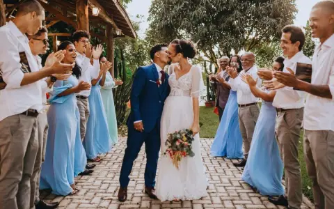 Un couple s'embrasse lors d'un mariage intime, entouré d'invités applaudissant.