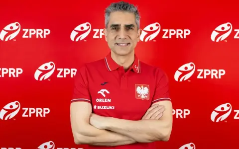 Uśmiechnięty mężczyzna, były trener piłkarzy ręcznych, w czerwonej koszulce z godłem Polski i logo ZPRP.