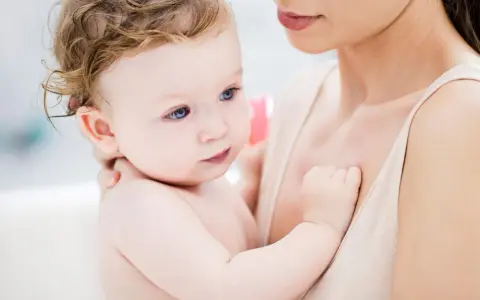 Ein Baby mit blauen Augen und zerzaustem Haar wird von seiner Mutter gehalten. Es ist fast 46 Wochen alt und durchläuft einen Entwicklungsschub.