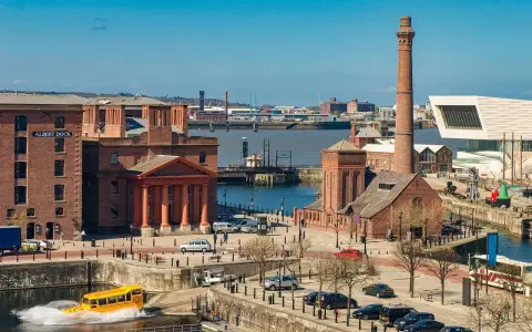 Albert Dock in der Liverpool Stadt, mit einem gelben Amphibienfahrzeug im Wasser und einem hohen Schornstein.