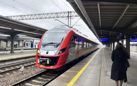 Czerwono-szary pociąg POLREGIO na peronie dworca kolejowego.