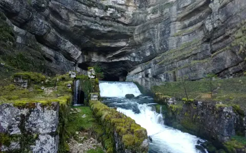 La source de la Loue, un spectacle naturel impressionnant. L'itinéraire mène à travers ce paysage rocheux où l'eau jaillit d'une grotte.