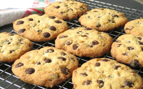 Un montón de galletas con pepitas de chocolate recién horneadas, doradas y deliciosas, enfriándose en una rejilla.