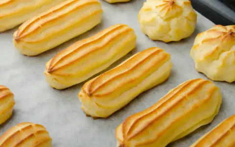 Des éclairs et des choux dorés, prêts à être garnir. La pâte à choux est prête pour une gourmandise.