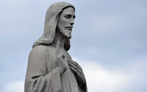 Kamienna rzeźba Jezusa z podniesionym palcem, jakby w geście błogosławieństwa lub modlitwy o pracę.