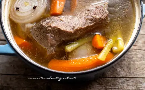 Brodo di carne ricetta della nonna in pentola: carne, carote, sedano e cipolla con chiodi di garofano. Profumo di casa.