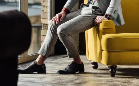 Eleganckie, ciemnobrązowe buty męskie do szarego garnituru w kratę. Stylizacja idealna na co dzień i specjalne okazje.