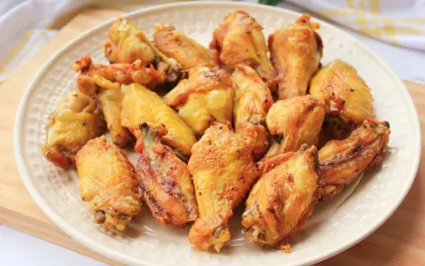 Alitas de pollo doradas y crujientes en un plato blanco.
