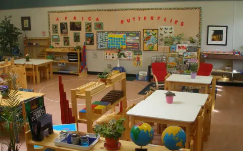Klasa przygotowana zgodnie z metodą Montessori: globusy, książki o Afryce i motylach, materiały edukacyjne na półkach.
