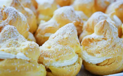 Une assiette de choux à la crème, saupoudrés de sucre glace. Ces petites merveilles de chou patisserie sont prêtes à être dégustées.