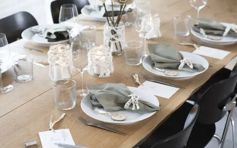 Vacker dukning med gröna servetter, ljus och blommor. Perfekt fest dekoration inspiration för ett stilrent hem.