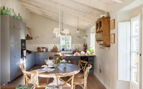 Cocina rústica y acogedora. Ideas para decorar casa vieja de pueblo con poco dinero. Techos de madera, muebles grises y mesa redonda.