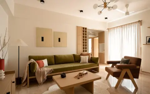 Soggiorno in stile Japandi con divano verde, poltrona in pelle, tavolino in legno e opere d'arte minimaliste.