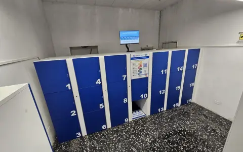 Blue and white numbered luggage lockers with a digital screen and instructions.