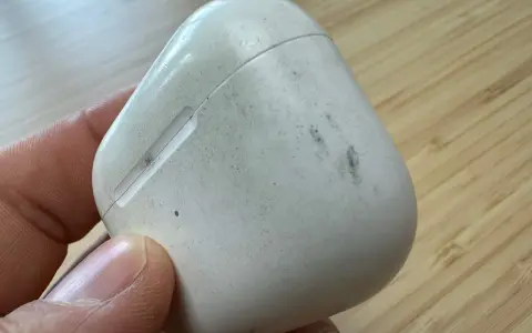 Eine schmutzige weiße Hülle für AirPods wird von einer Hand gehalten.