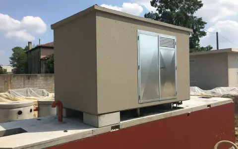 Edificio prefabbricato con porte metalliche, probabilmente per ospitare una pompa soprabattente, su una base in cemento.