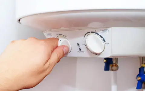 Mano ajustando el dial de potencia de un termo eléctrico. Si el termo pita, puede ser por un ajuste incorrecto de temperatura o por un problema de calentamiento.