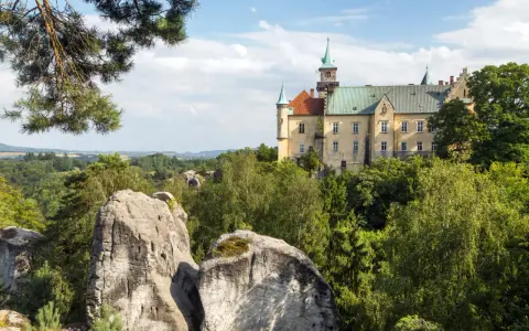 Zamek Hrubá Skála, wspaniały przykład tego, co warto zobaczyć w Czechach, wznosi się nad skalistym krajobrazem i bujną zielenią.