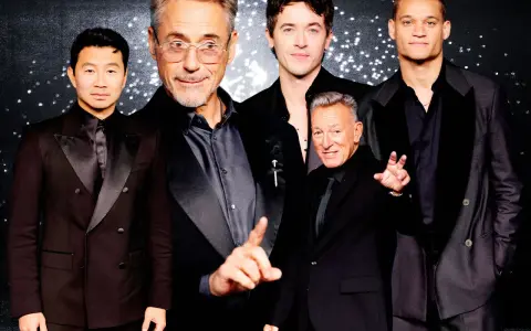 Five men in black suits with black shirts pose for a photo.
