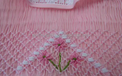 Detalle de puntada smock en tela rosa, con flores bordadas. Aprende como hacer punto smock.