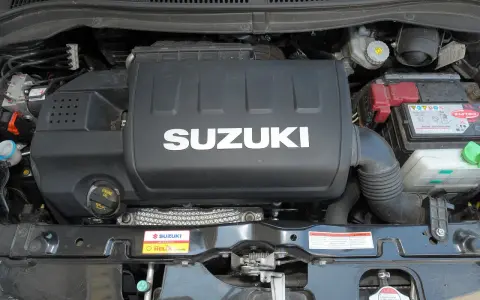Silnik Suzuki Swift 2007 z widocznym logo SUZUKI na pokrywie. Widać akumulator i elementy układu dolotowego.