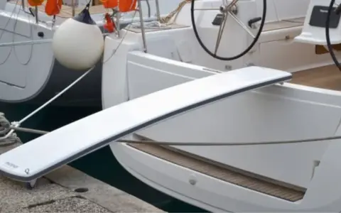 Eine selbstgebaute Gangway für Boote, die über eine Reling gelegt wird.