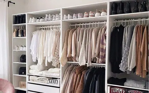 Armarios blancos perfectamente organizados con ropa y zapatos ordenados. Un ejemplo de cómo organizar armarios para un espacio funcional y estético.