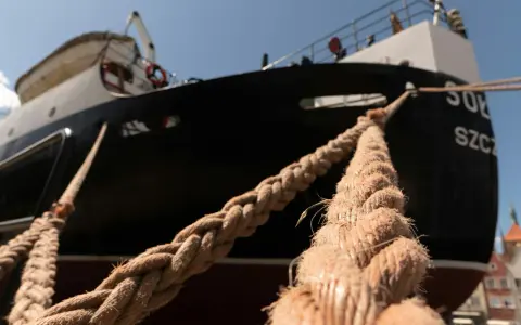 Gros cordage tressé, essentiel au point d'amarrage d'un navire noir et blanc sous un ciel bleu.